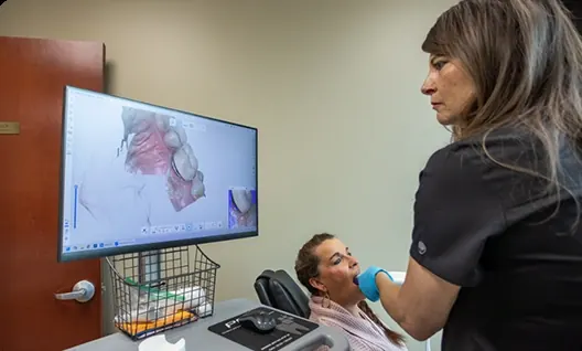A team member reviewing a 3-D digital scan with a patient in the chair.